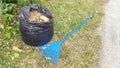 lawn sweepers and plastic trash filled with dry grass and twigs on the side of the road