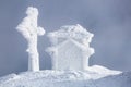 On the lawn there is wooden church covered with snow high on the mountains. Fog on the background. Fantasy winter landscape