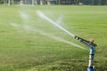 lawn water sprinkler in action spraying water in field Royalty Free Stock Photo