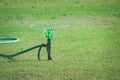 Lawn Water Sprinkler On Green Grass Spraying And Watering Meadow At Outdoor Garden In Summer Seasonal.