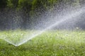 Lawn water sprinkler spraying water over grass in garden on a hot summer day. Automatic watering lawns. Gardening and environment Royalty Free Stock Photo