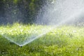 Lawn water sprinkler spraying water over grass in garden on a hot summer day. Automatic watering lawns. Gardening and environment Royalty Free Stock Photo