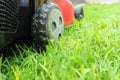 Lawnmover on on a grassy grass. An old red lawn mower mowing lush green grass Royalty Free Stock Photo