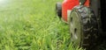Lawnmover on on a grassy grass. An old red lawn mower mowing lush green grass Royalty Free Stock Photo