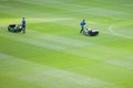 The lawnmower man mows the lawn in a football stadium before the game. Men in baseball caps prepare the field for football games Royalty Free Stock Photo