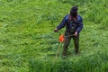 Lawnmower man with string trimmer and face mask trimmong grass - close-up Royalty Free Stock Photo