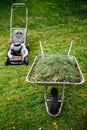 lawnmower and wheelbarrow with grass on mown lawn