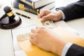 Lawyer being offered receiving money as bribe from client at desk in courtroom Royalty Free Stock Photo