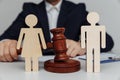 Lawyer or counselor holds gavel behind of figures of young family, divorce or separation concept Royalty Free Stock Photo