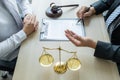 Lawyer hand holding pen and providing legal consult business dispute service at the office with justice scale and gavel hammer Royalty Free Stock Photo