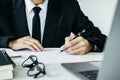 The lawyer, handwriting civil and criminal indictment on the desk with laptop and glasses working at the home office