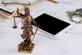 Lawyer office Statue of Justice with scales and lawyer working on a digital tablet