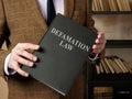 Lawyer in suit holds Defamation law book.