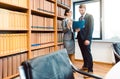 Lawyers in library of law firm discussing strategy in a case holding file Royalty Free Stock Photo