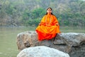 LAXMAN JHULA, INDIA - APRIL 19, 2017: A Hindu saint in orange sitting at the Ganges in India