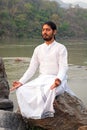 LAXMAN JHULA, INDIA - APRIL 19, 2017: A Hindu swami in white sitting at the Ganges in India