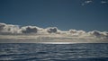 layer of cumulus clouds under a blue sky over the ocean with bright sun reflections Royalty Free Stock Photo