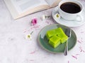 Layer sweet cake on a plate and a cup of white coffee with a book on gray stone background Royalty Free Stock Photo