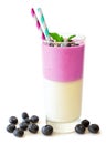 Layered blueberry and coconut smoothie with scattered berries over white