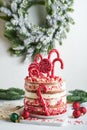 Layered Christmas gingerbread cake decorated with red Lolli pops, colored confetti on white cake stand, Christmas balls, fir