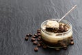 Layered creamy cappuccino cheesecakes in glass jar on black stone background