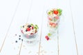 Layered dessert with raspberry, strawberry, black currant and kiwi, cream and biscuits in glasses