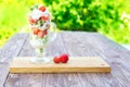 Layered dessert with strawberries and cream cheese on wooden table over green garden background Royalty Free Stock Photo