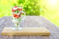layered dessert with strawberries and cream cheese on wooden table over green garden background Royalty Free Stock Photo