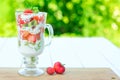 Layered dessert with strawberries and cream cheese on wooden table over green garden background Royalty Free Stock Photo