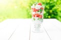 layered dessert with strawberries and cream cheese on wooden table over green garden background Royalty Free Stock Photo