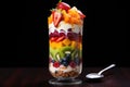 layered fruit salad in a tall glass with a spoon