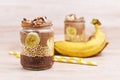 Layered healthy dessert with banana fruit slices, puffed quinoa grain and chocolate chia seed pudding in jar