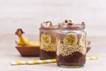 Layered healthy dessert with banana fruit slices, puffed quinoa grain and chocolate chia seed pudding in jar