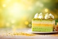 Layered matcha biscuit cake with pistachio and mango souffle on colored blurred boken background. Healthy sweet food concept.