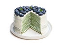 Layered matcha pancake cake with cream and blueberry isolated on white