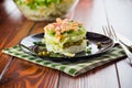 Layered salad of cabbage and other vegetables with pieces of red fish in a plate. Royalty Free Stock Photo