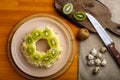 Layered salad with chicken and kiwi nuts next to quail eggs on a kiwi napkin on a board and a knife.