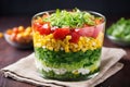a layered salad in a glass bowl showing distinct vegetable layers