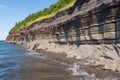 layered sedimentary cliff around a beach area