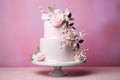 Layered wedding cake with flower decoration on pink studio background