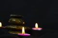 Layers of stones are on dark background, two rounded candles, use for massage and yoga obect concept