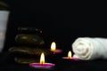 Layers of stones are on dark background, two rounded candles with white towel, use for massage and yoga obect concepts