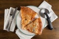 Two slices of double crust large speciality Chicago pizza on wooden table with napkins