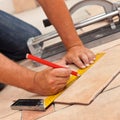 Laying ceramic floor tiles - man hands marking tile to be cut, c Royalty Free Stock Photo