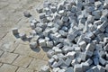 Laying granite and marble light, white gray, medium size cubes. tilers put cobblestones in sand or gravel. they have piles ready t