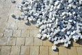 Laying granite and marble light, white gray, medium size cubes. tilers put cobblestones in sand or gravel. they have piles ready t