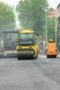 Laying of new asphalt on a city street. Large equipment for laying and tamping asphalt is working on the road. The use of a roller