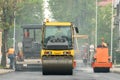 Laying of new modern asphalt. Asphalt laying equipment works on the site. A yellow asphalt skating rink rides in close-up on a new Royalty Free Stock Photo