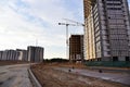 Laying paving slabs and borders at construction site. Tower cranes in action with machinery and builders. Crane build the high- Royalty Free Stock Photo