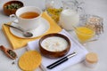 Layout of a cup of herbal tea, a face mask in a wooden bowl, a jug of milk, oatmeal, honey and herbs on a light background. Spa Royalty Free Stock Photo